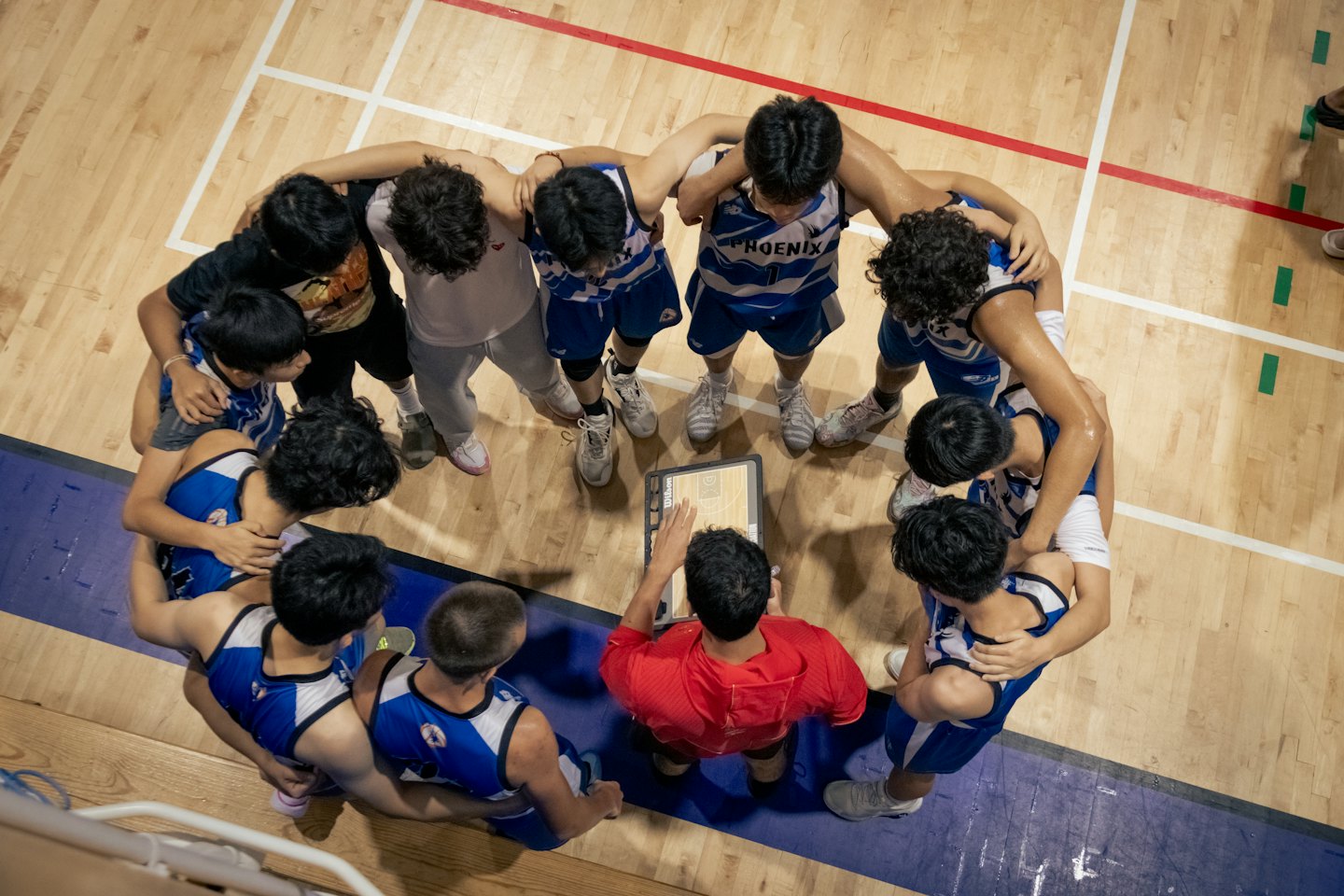 Un entraîneur de basketball explique une stratégie à son équipe sur le terrain.