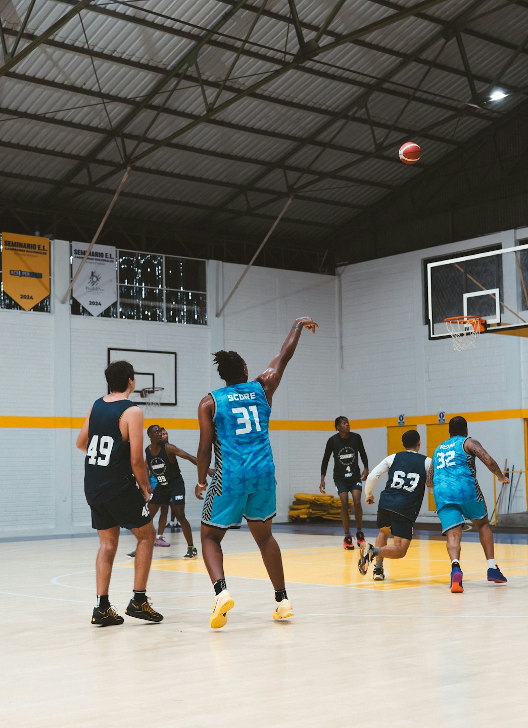 Un joueur de basket-ball en maillot bleu tire vers le panier.